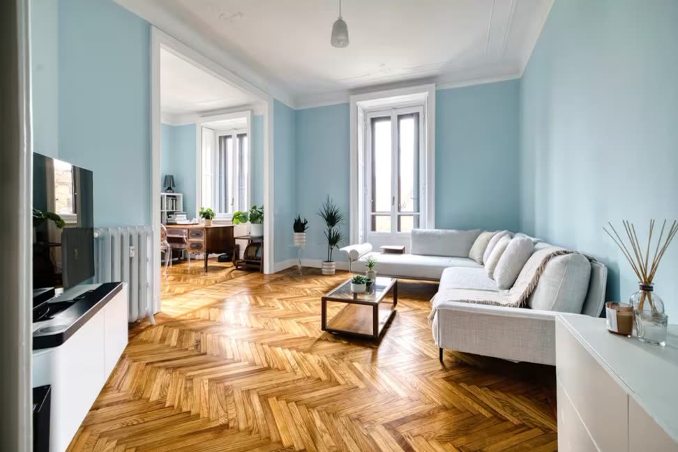 Bright period living room with pale blue walls, herringbone parquet floor and a cream corner sofa