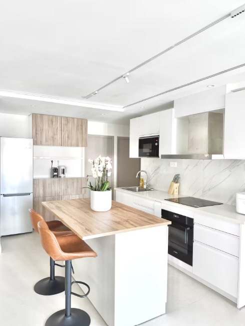 White kitchen with a wood island and bar stools